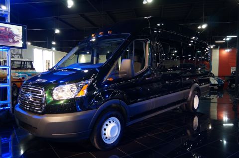1993 Ford Taurus - A dark green van is displayed indoors, with other vehicles visible in the background.