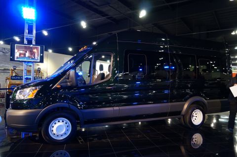 1993 Ford Taurus - A dark green van is displayed indoors on a shiny black floor with blue lighting.