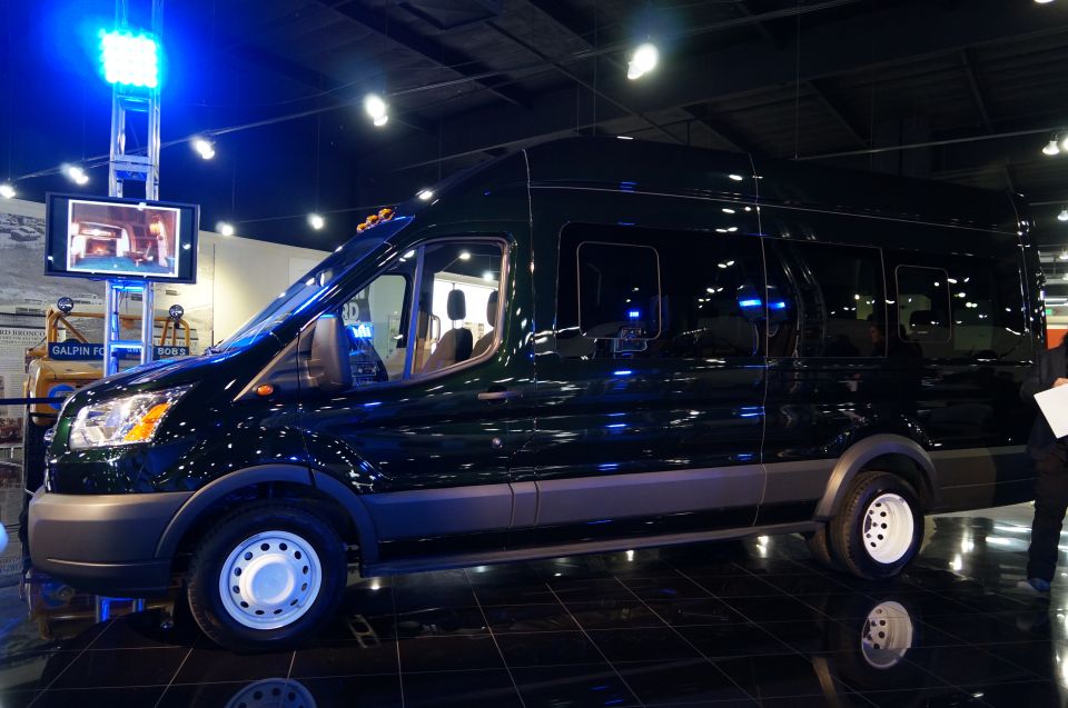 Dark green van with tinted windows parked indoors on a reflective floor