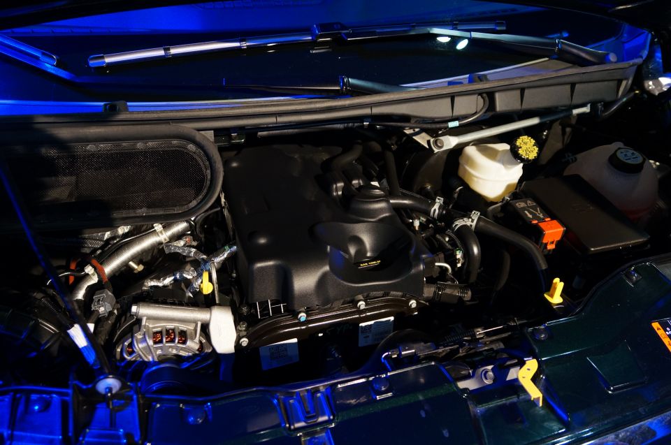 Engine bay with black engine cover, air intake, and fluid reservoirs