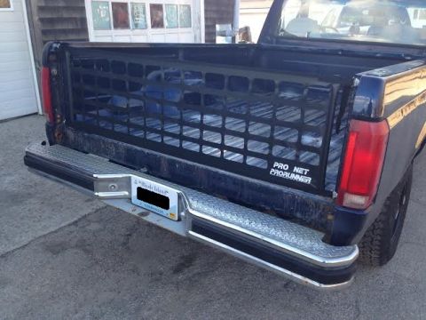 2004 Ford Crown Victoria - Rear view of a dark blue pickup truck a cargo net in the bed and a chrome bumper with a 'PRO NET PRORUNNER' decal.