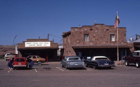 1991 Ford LTD Crown Victoria - The United States Post Office in Cameron, Arizona, with an American flag flying and several vehicles parked in front.