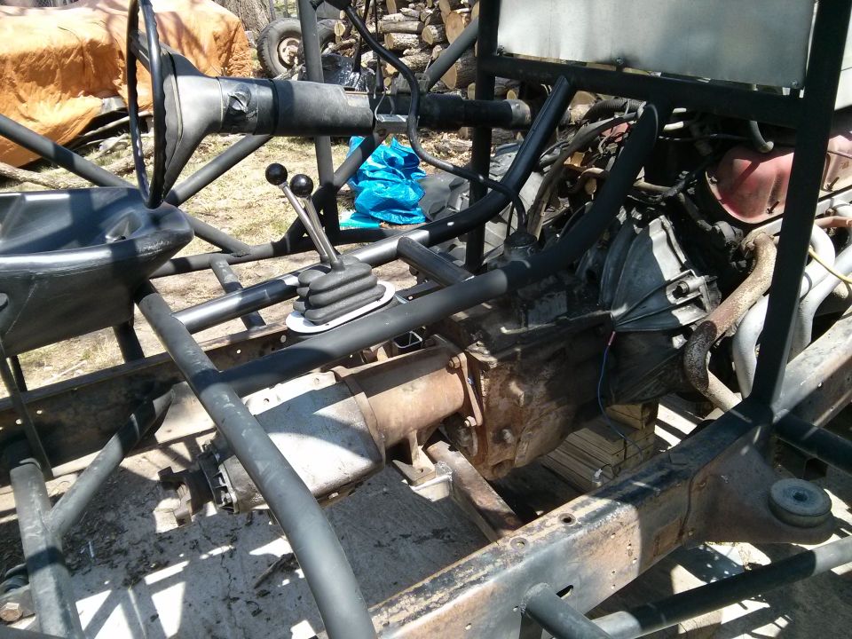 Off-road vehicle chassis showing transmission, steering column, and shifter. Frame is exposed