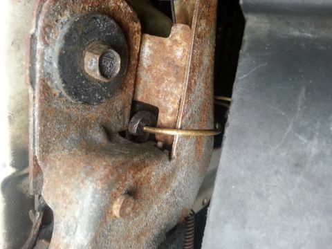 1995 Ford Bronco - This image shows a close-up view of a rusted metal bracket with a bolt and a piece of wire.