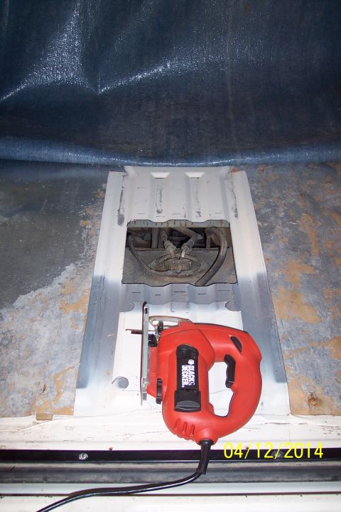 1990 Ford Bronco - A jigsaw rests beside an open fuel tank access panel, revealing internal components.