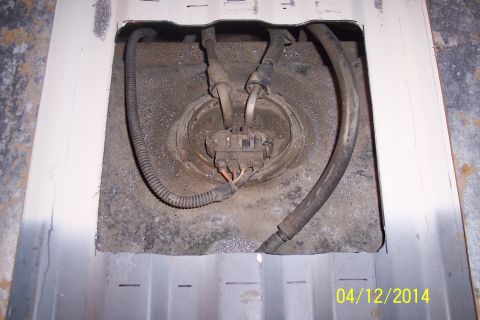1990 Ford Bronco - The fuel pump assembly is exposed through an access panel in the vehicle's body.