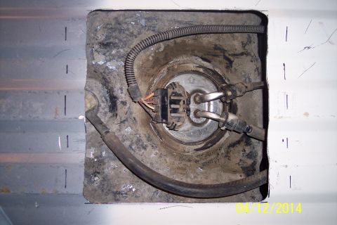 1990 Ford Bronco - Close-up of a vehicle's fuel pump access panel, showing the pump assembly and associated wiring.