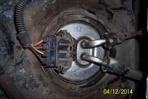 1990 Ford Bronco - Close-up view of a vehicle's fuel pump access panel, showing the electrical connector and fuel lines.