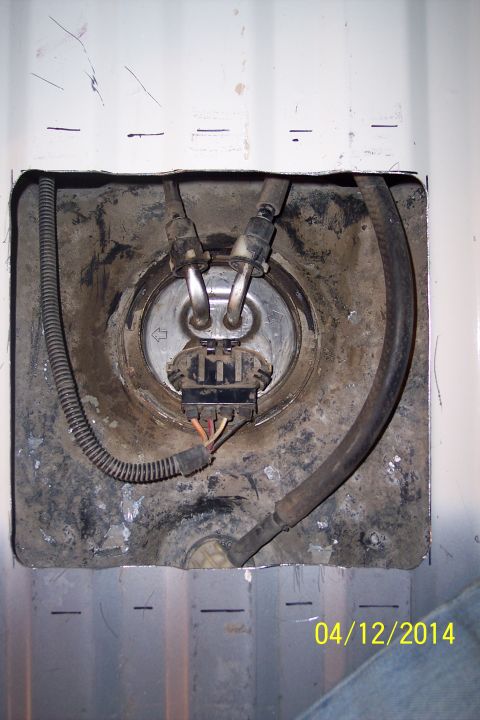 1990 Ford Bronco - Access panel reveals the vehicle's fuel pump assembly, including fuel lines and wiring harness.