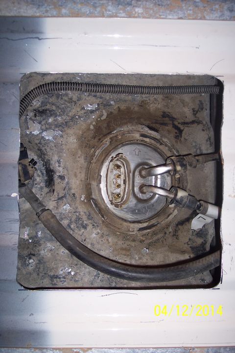 1990 Ford Bronco - Access hole for the fuel pump assembly, showing hoses and electrical connections.