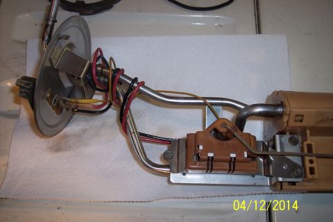 1990 Ford Bronco - Fuel pump sending unit with associated wiring and metal arm, resting on a white paper towel.