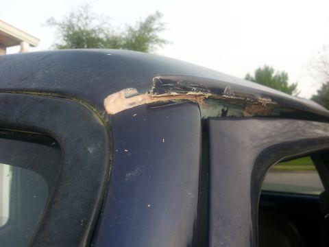 1994 Ford Bronco - Close-up of damaged roof trim on a dark blue vehicle, showing areas of rust and repair.
