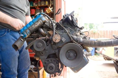1964 Mercury Monterey - Engine assembly with blue valve cover and various hoses and pulleys, held by a person.