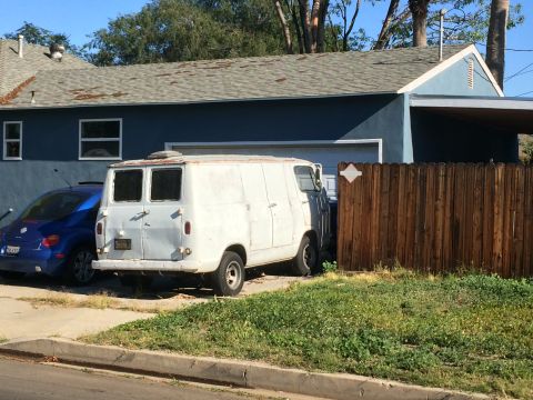 1968 Ford Mustang - A white van and a blue car are parked in a driveway next to a house.