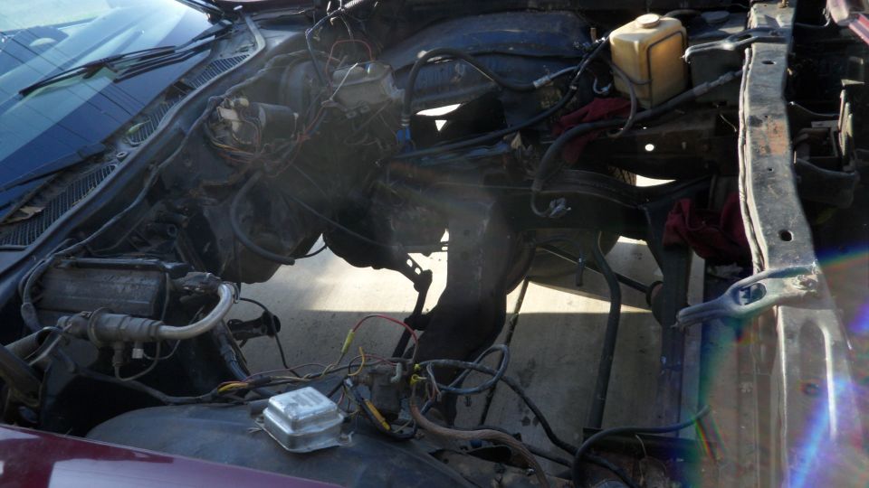 Engine bay of a car with the hood open, showing the engine and various hoses and wires