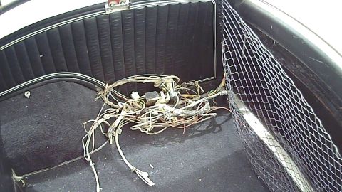 1978 Ford Bronco - A messy wiring harness and mesh storage net are visible inside the rear of a vehicle.