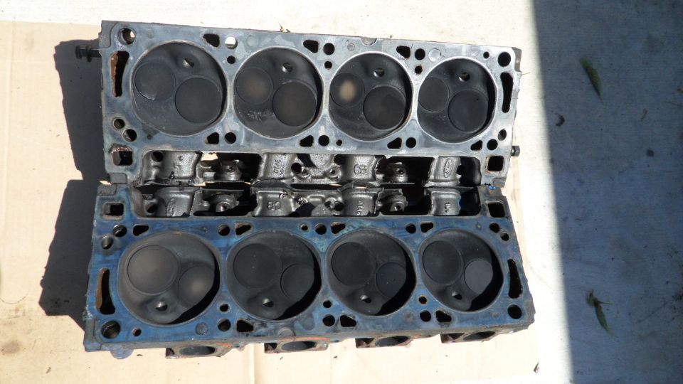 Two engine cylinder heads with visible valves and combustion chambers, resting on a surface