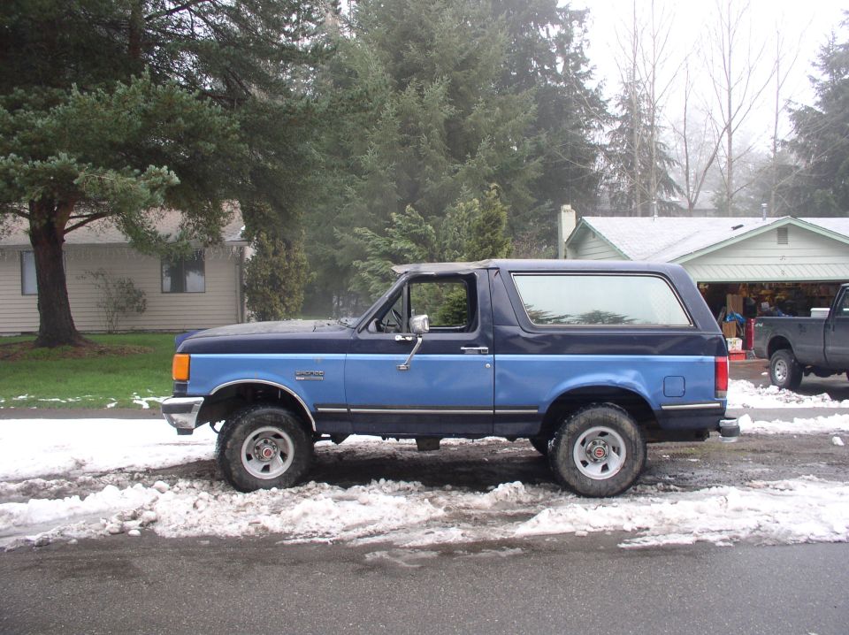 Blue and dark blue two-tone Ford Bronco parked on a snowy road