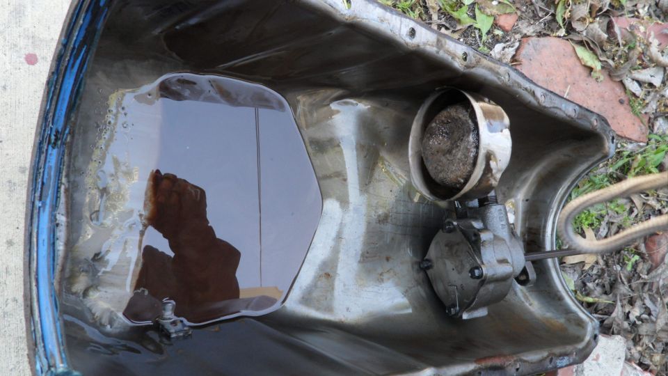 Oil pan with dark oil and a small oil pump assembly attached