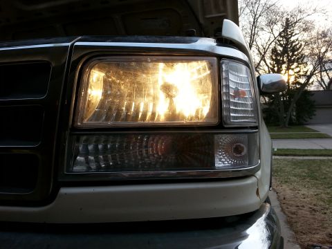 1995 Ford Bronco - Close-up of the illuminated front headlight and grille of a 1995 Ford Bronco.