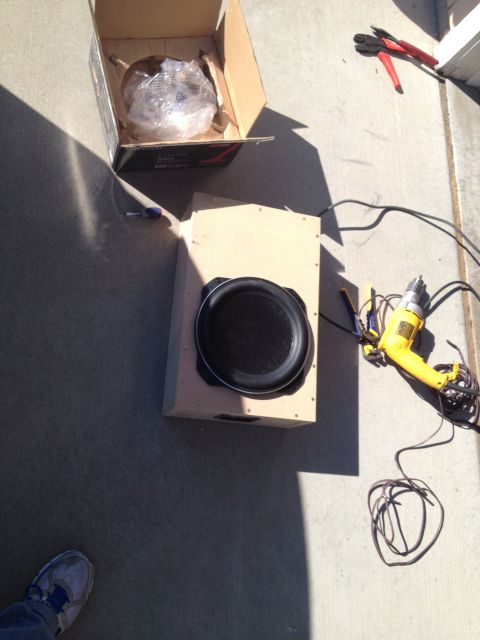 2005 Jeep Wrangler - A car stereo subwoofer is shown next to a drill and wire cutters on a concrete surface.