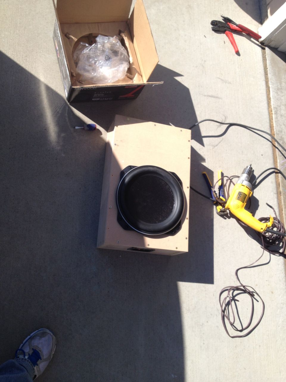 Subwoofer in a box with a drill and wire cutters nearby