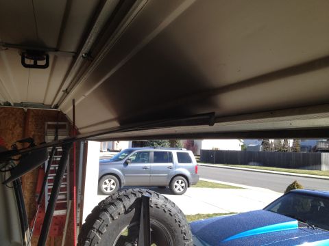 2005 Jeep Wrangler - View from inside a garage shows a spare tire and a silver SUV parked outside.
