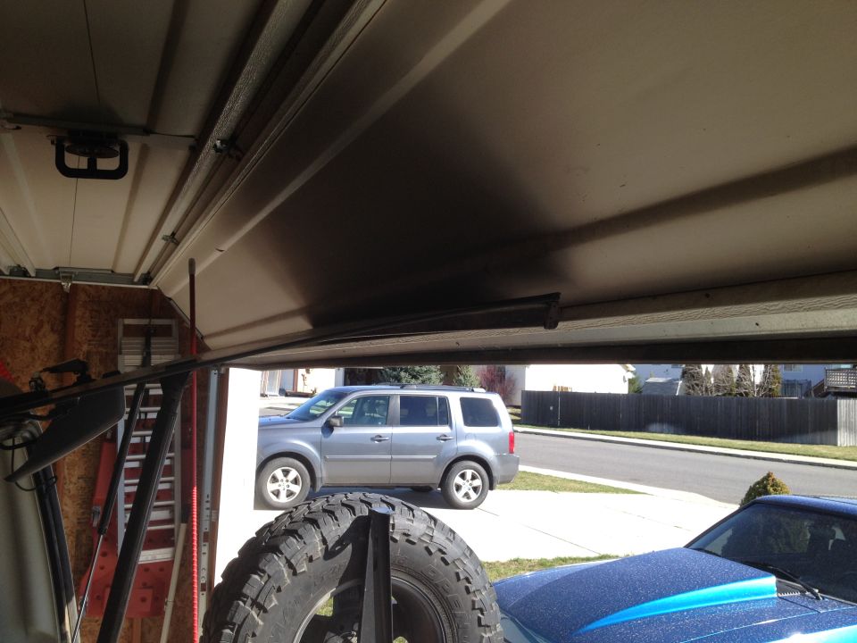 Spare tire in foreground, silver SUV parked outside garage