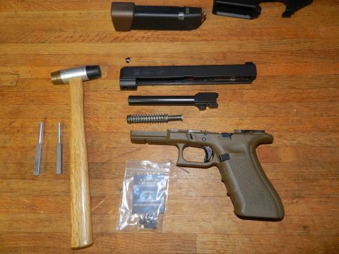 1996 Ford Bronco - A handgun is disassembled into its component parts, including the frame, slide, barrel, and spring, alongside a hammer and punches.