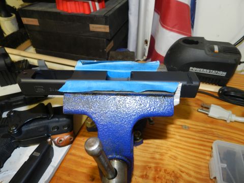 1996 Ford Bronco - Gun slide being worked on in a vise, with a power station and flag visible.