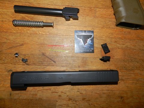 1996 Ford Bronco - Disassembled handgun components are arranged on a wooden table, including a slide, barrel, and recoil spring assembly.