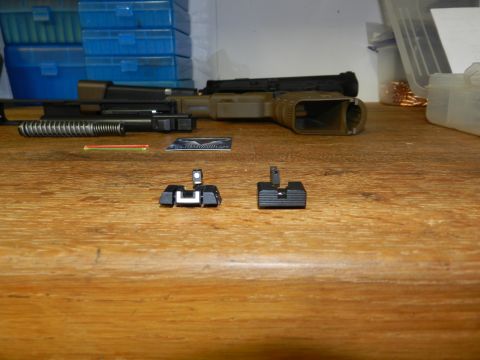 1996 Ford Bronco - Disassembled firearm parts and two gun sights are laid out on a wooden table.