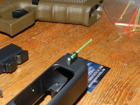 1996 Ford Bronco - Disassembled gun parts, including a frame with a fiber optic front sight, are laid out on a wooden surface.