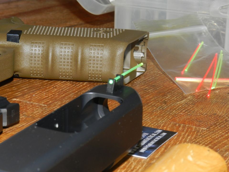 Pistol slide with fiber optic front sight, tan pistol frame, and bag of replacement sights