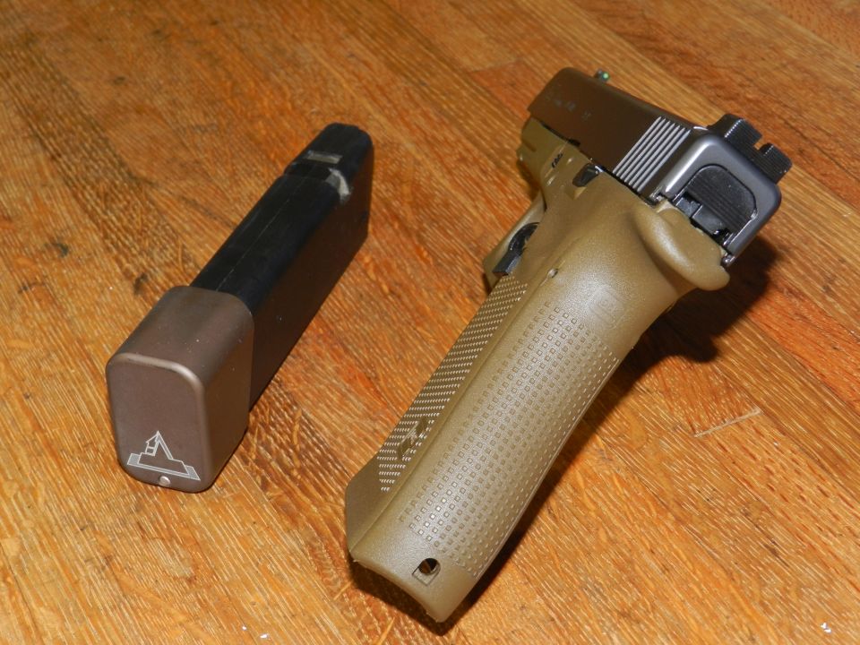 Tan pistol with extended magazine on wooden surface