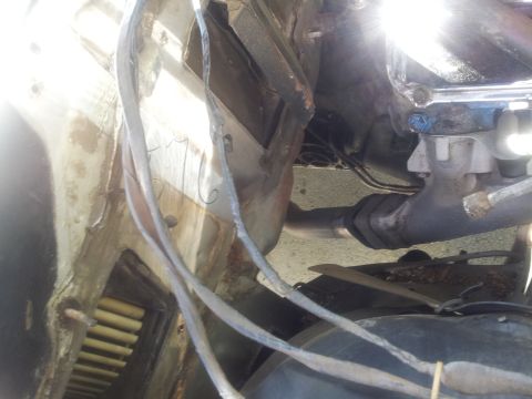 1976 Ford Ranchero - The photo shows a section of an engine bay, focusing on exhaust and wiring, with some scratched numbers on a panel.