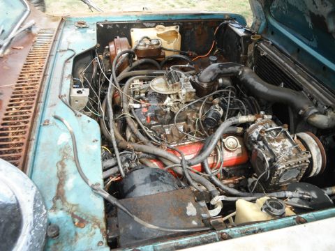 1972 International Scout II - The engine bay of a 1972 International Scout II shows a V8 engine and signs of wear and tear.