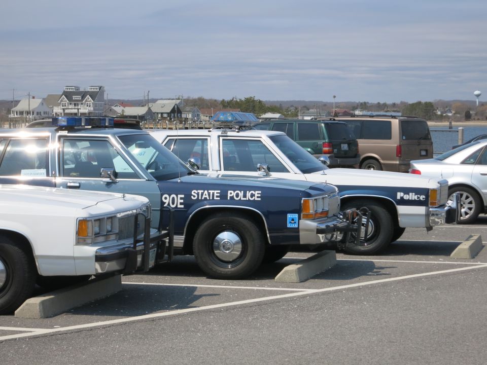 Close row of police cars, blue 90E STATE POLICE Ford cruiser at center