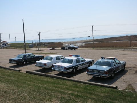 1991 Ford LTD Crown Victoria - Four vintage sedans parked rear-in, including Boston and State Police cruisers, with a Highway Patrol car behind.