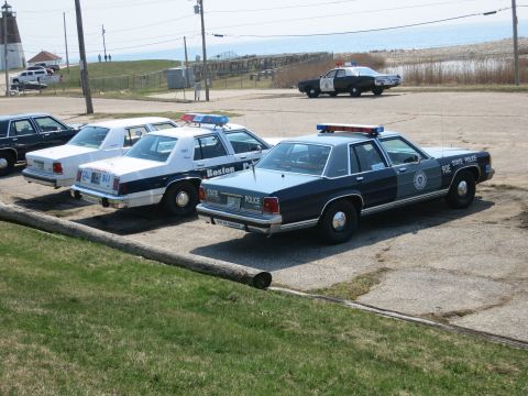 1991 Ford LTD Crown Victoria - Boston Police and State Police Ford sedans parked in a row at a waterfront lot with a squad car beyond.