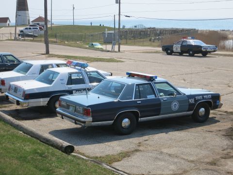 1991 Ford LTD Crown Victoria - Massachusetts State Police Ford sedan marked 90E parked beside a Boston Police car at a coastal lot.