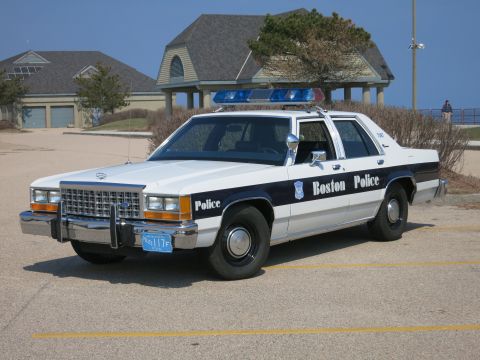 1991 Ford LTD Crown Victoria - Boston Police Ford LTD Crown Victoria sedan photographed front three-quarter in a paved lot with houses behind.