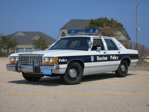 1991 Ford LTD Crown Victoria - white and blue Boston Police Ford LTD Crown Victoria sedan parked in a paved lot under clear sky with houses behind.