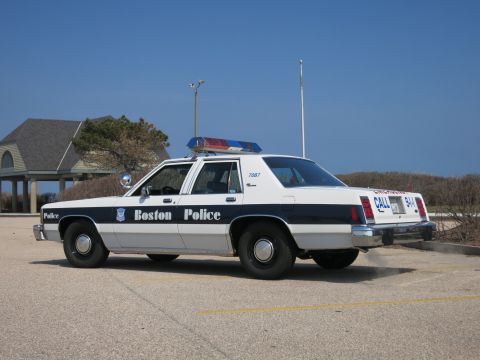 1991 Ford LTD Crown Victoria - Boston Police Ford LTD Crown Victoria sedan from the rear three-quarter showing the CALL 9-1-1 trunk lettering.