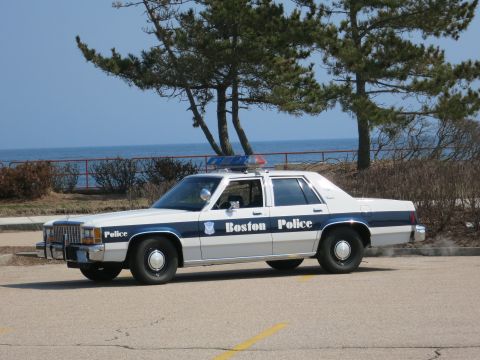 1991 Ford LTD Crown Victoria - Boston Police Ford LTD Crown Victoria sedan in driver-side profile parked at a lot overlooking the sea and trees.