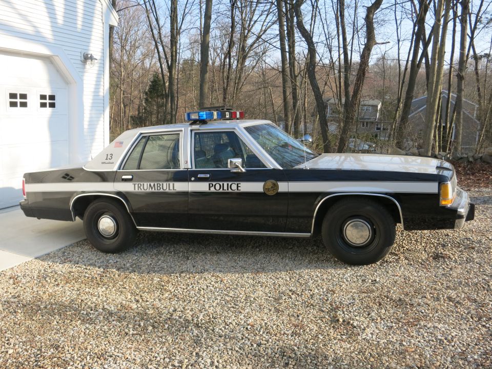 Driver-side profile of a black and white Trumbull Police Ford sedan