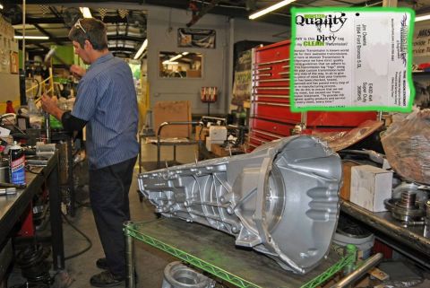 1994 Ford Bronco - A mechanic works in a workshop with a large transmission part on display.