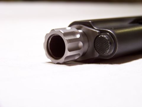 1995 Mercury Grand Marquis - Close-up of a gun barrel and slide, showing the fluted muzzle and a textured button on the side.