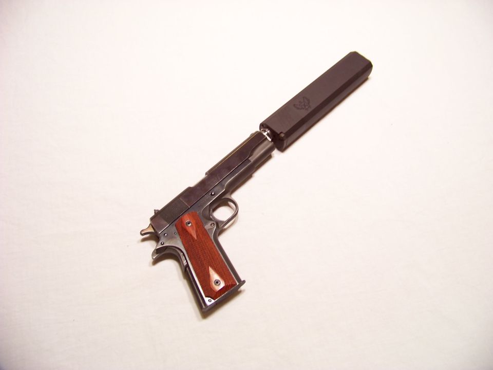 pistol with wooden grips and a silencer attached to the barrel