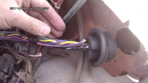 1978 Ford Bronco - A hand is shown adjusting a bundle of wires connected to a black grommet.